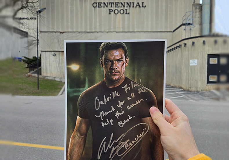 Film Pilot Program Signed Reacher poster held up in front of the Centennial Pool building.